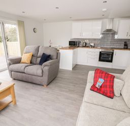 An open plan living room and kitchen with two sofas and a coffee table at Beechnut Cottage in Tewkesbury