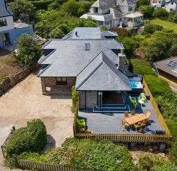 Aerial view of a house with a deck featuring outdoor seating and a hot tub surrounded by greenery at Rocky Close in St Ives