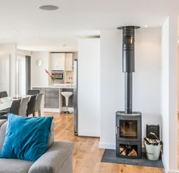 An open living room and kitchen area with a wood burning stove and dining table at Boscarne St Ives