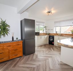 A kitchen with a wooden dresser and plants near windows at 4 Bodnant Road in Rhos-On-Sea