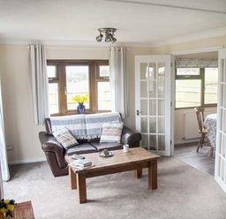 A living room with a brown leather sofa coffee table and flowers on a side table at The Dovecote in Hartland