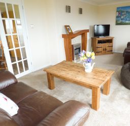 A living room with brown leather sofas a wooden coffee table a fireplace a television on a wooden stand and a bean bag at The Dovecote in Hartland