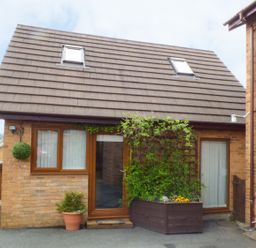 A brick house with two skylights two windows a glass door and plants outside at Penylodge in Builth Wells