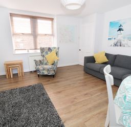 A living room with a gray sofa and patterned armchair with yellow cushions at Sunnie Cottage in Seahouses