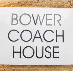 A sign with the text Bower Coach House on a stone wall at Bower Coach House in Bower Hinton near Martock