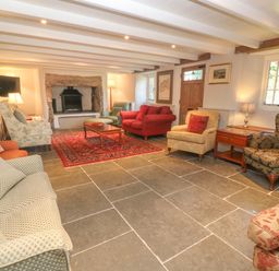 A living room with multiple armchairs a sofa a coffee table a fireplace and a red rug at Ros Vale in St Buryan