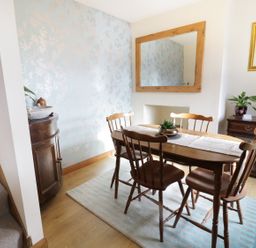 A dining room with wooden table and chairs a large mirror on the wall and a staircase at 60 Hyfrydle Road Talysarn near Caernarfon