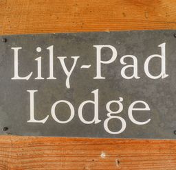 A metal sign with Lily-Pad Lodge mounted on a wooden wall at Lily-pad Lodge in Thorpe-on-the-Hill