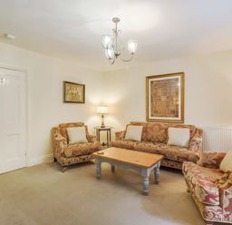 A living room with patterned sofas a wooden coffee table wall art and lamps at Gardeners Cottage in Bellingham