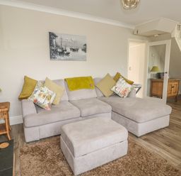 A living room with a sectional sofa and ottoman next to a side table and lamp at Bertelle in Grimston