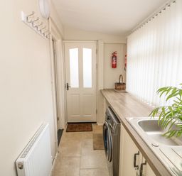 A laundry room with a washing machine sink and plant near a door at Bertelle Grimston