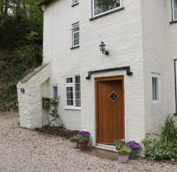 Exterior view of a white brick house with a wooden door and several flower pots at Town Mill in Bewdley
