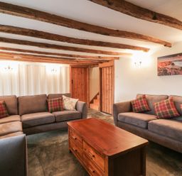 A sitting room with wooden beams on the ceiling two sofas and a wooden coffee table at Lower West Curry Farmhouse in Launceston
