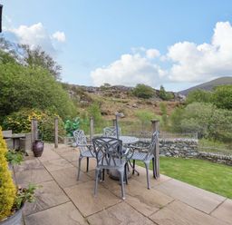 An outdoor terrace with a table and chairs at Moelfre Cottage Llanbedr