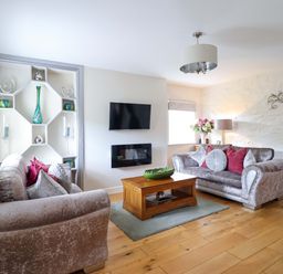 A living room with a sofa, tv, and coffee table at Moelfre Cottage in Llanbedr