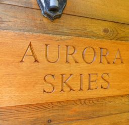 A wooden sign with the text Aurora Skies mounted on a wooden wall at Aurora Skies in Cresswell near Morpeth