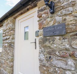 An entrance door with stone wall at Gallow Law Cottage in Bellingham