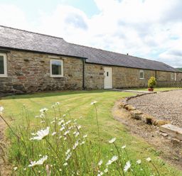A stone building with windows and grass at Shepherds Burn Cottage in Bellingham