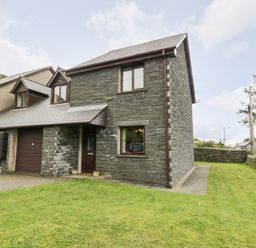 A stone house with a small front yard and garage in Manod near Blaenau Ffestiniog