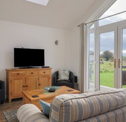 A snug room with a sofa and television at Keepers Cottage in Sidmouth