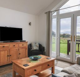 A living room with a television and wooden furniture at Keepers Cottage in Sidmouth