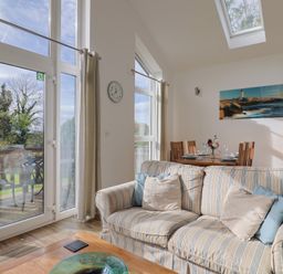 A living room with a sofa and dining area at Keepers Cottage in Sidmouth
