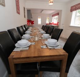 A dining room with a long wooden table set with bowls plates glasses and cutlery at Dumbuie in Haltwhistle