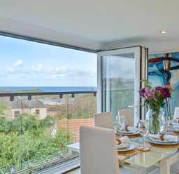 A dining room with a table set for meals at Sunset View in Porth