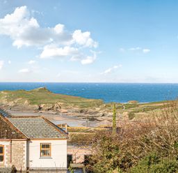 A view of the ocean and cliffs near a house at Sunset View in Porth