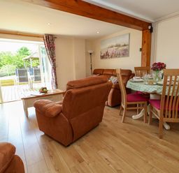 A living room with a dining area and a sliding door at Mallows Byre in Yetminster