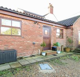 An exterior view of a brick building with two windows a door and outdoor plants at The Ramblers Annex in Mattishall