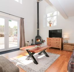A living room with a wooden coffee table a fireplace a TV on a dresser and sofas at Old Chapel in Cloughton