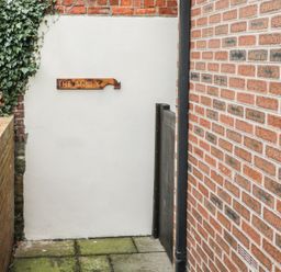 A narrow outdoor passage with brick walls and a wooden sign saying The Annex at The Annex @ Garden House Prudhoe near Newcastle