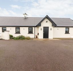 Exterior view of a single-story white cottage with black framed windows and door at Laharn Cottage in Killorglin County Kerry