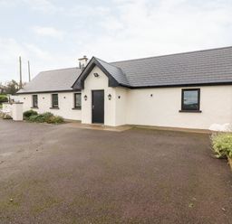 A front view of a white cottage with a black door and roof at Laharn Cottage in Killorglin County Kerry