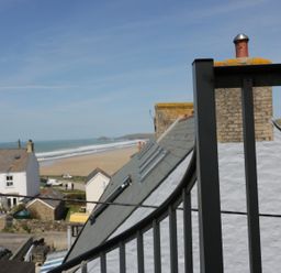 A coastal view showing rooftops of houses near a beach with ocean waves at Spiral View in Perranporth
