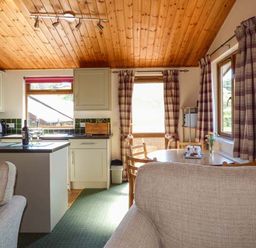 A kitchen and dining area with a round table chairs and curtains at North Lodge in Kendal