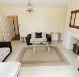 A living room with two sofas a glass coffee table a rug a white fireplace and a large mirror at Garden View in Malvern