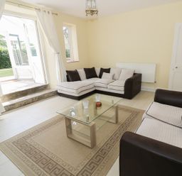 A living room with two sofas a glass coffee table and an open door leading outside at Garden View in Malvern