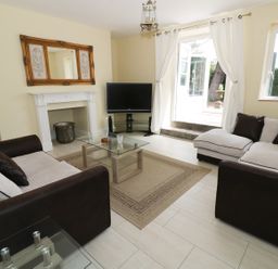A living room with two sofas a glass coffee table a TV and an open door to a garden at Garden View in Malvern