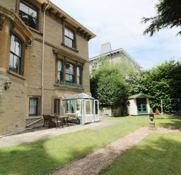 An outdoor garden area with a stone house, patio furniture, a small greenhouse, a playhouse, and a swing set at Garden View in Malvern