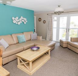 A living room with beige leather sofas and a wooden coffee table at Harbour View in Cemaes Bay