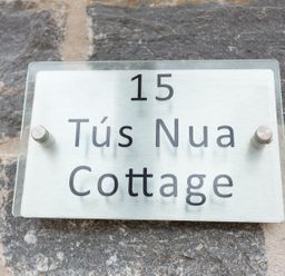 A house number sign reading 15 Tus Nua Cottage mounted on a stone wall at Tus Nua Cottage in Carhampton