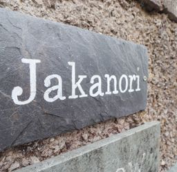 A slate stone nameplate with the word Jakanori mounted on a rough textured wall outside a residential area at Jakanori in Staveley