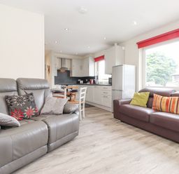 A living room with two sofas and pillows next to a kitchen with cabinets and a dining table at Jakanori in Staveley