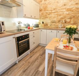 A kitchen with white cabinets wooden countertops a dining table set with breakfast at Lowdale Barns West Sleights