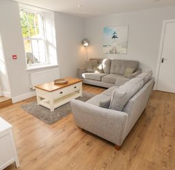A living room with two gray sofas a wooden coffee table and a lamp at Harbour Beach at The Hideaway in Tenby