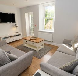 A living room with two sofas a coffee table a rug and a wall-mounted television at Harbour Beach at The Hideaway in Tenby