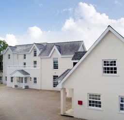 White two story residential buildings with multiple windows and a red mailbox under a blue sky at North Beach at The Hideaway in Tenby