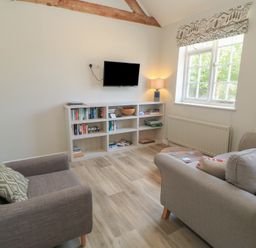 A living room with a television and bookshelves at The Cider Press, Motcombe